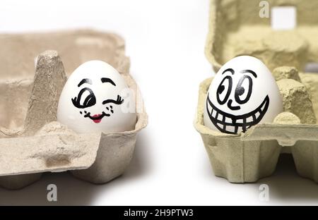 Close up of two eggs with painted faces a woman with a man funny flirting isolated on white background Stock Photo