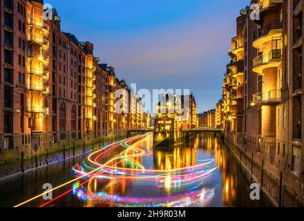 Night shot of the moated castle and an excursion ship with fairy lights in the Speicherstadt, Hamburg, Germany Stock Photo