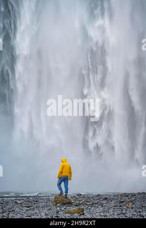 Huge waterfall behind a person, Skogafoss waterfall, South Iceland, Iceland Stock Photo