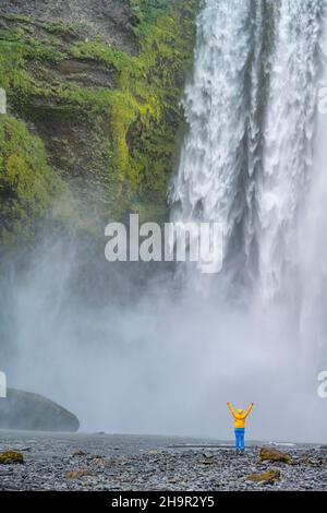 Huge waterfall behind a person, Skogafoss waterfall, South Iceland, Iceland Stock Photo