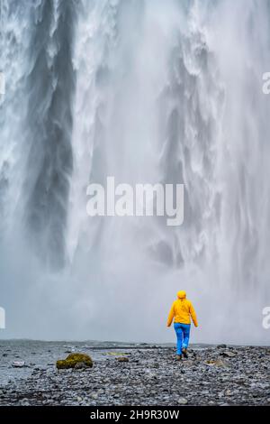 Huge waterfall behind a person, Skogafoss waterfall, South Iceland, Iceland Stock Photo