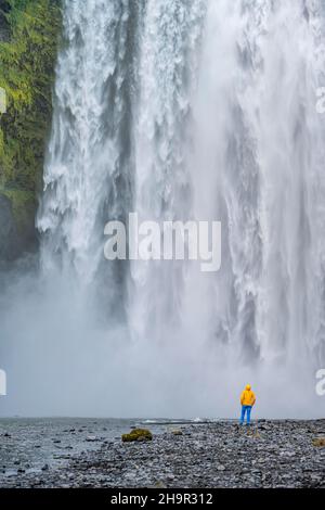 Huge waterfall behind a person, Skogafoss waterfall, South Iceland, Iceland Stock Photo