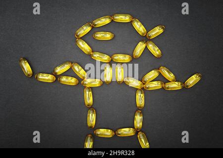 Fish oil softgels arranged into an anthropomorphic athlete character flexing the biceps. Fatty acids dietary supplement and its impact on athletic per Stock Photo