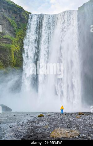 Huge waterfall behind a person, Skogafoss waterfall, South Iceland, Iceland Stock Photo