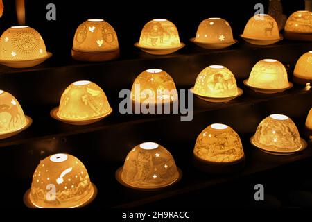 Rows of semi-circle ceramic lanterns lit by candlelight and decorated with holiday iconography - Zurich Main Station Christmas Market, Switzerland Stock Photo