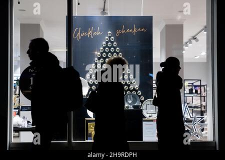 Berlin, Germany. 06th Dec, 2021. Passers-by walk past a Christmas-decorated shop window on a Berlin shopping street. Credit: Christoph Soeder/dpa/Alamy Live News Stock Photo