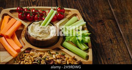 Hummus and vegetable sticks of carrot and celery on a wooden plate Stock Photo