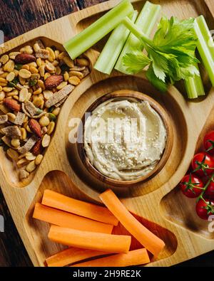 Hummus and vegetable sticks of carrot and celery on a wooden plate Stock Photo