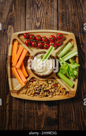 Hummus and vegetable sticks of carrot and celery on a wooden plate Stock Photo