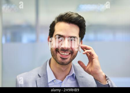 Smiling young businessman using bluetooth headset in mobile communication Stock Photo