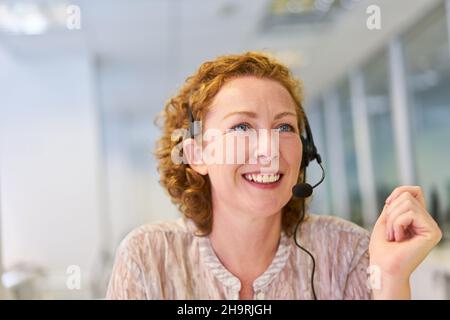 Young woman as operator with headset in the service hotline in the call center Stock Photo