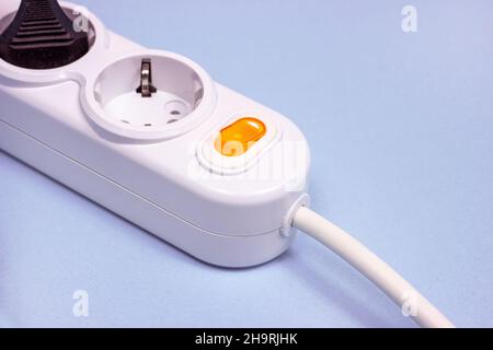 Triple socket white European power adapter with different wires at home. Standard electrical plug power outlet on blue background Stock Photo