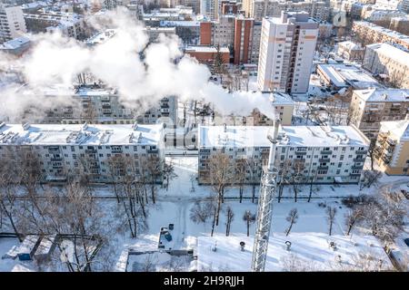 smoking chimney of thermal power plant on winter city background at cold sunny day Stock Photo