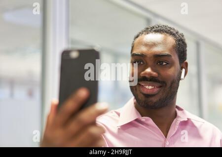 Young businessman video chat with smartphone and bluetooth headset Stock Photo