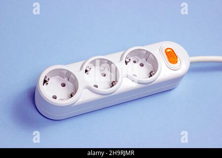 Triple socket white European power adapter with different wires at home. Standard electrical plug power outlet on blue background Stock Photo