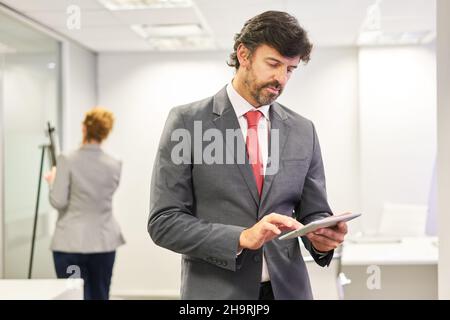 Business man as manager or boss doing research on tablet computer online in the office Stock Photo