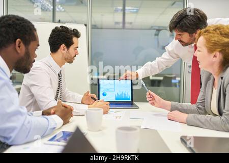 Consultant in meeting analyzing data and charts on laptop computer Stock Photo