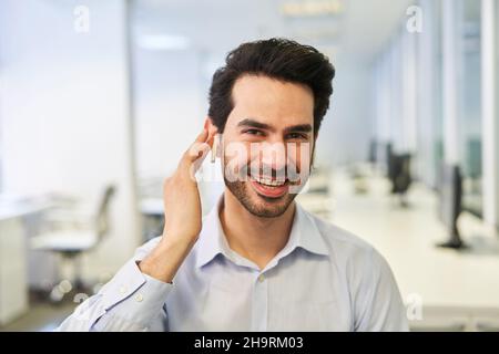 Happy young businessman as an entrepreneur with bluetooth headset in the office Stock Photo