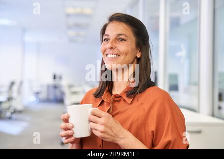 Satisfied young businesswoman having coffee during a break in the office Stock Photo