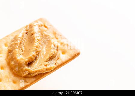 Crunchy peanut butter spread on soda crackers close up on the white background Stock Photo