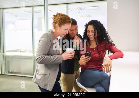 Three female friends as a team relax together during a coffee break in the office Stock Photo