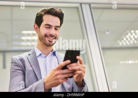 Smiling young business man reading or writing a text message on the smartphone Stock Photo