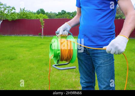 Electrician with extension coil in the backyard. Close-up. Stock Photo