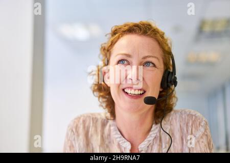 Friendly businesswoman with headset in the call center hotline as a customer service representative Stock Photo