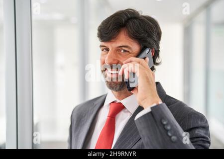 Smiling businessman as a manager or consultant talking on the mobile phone Stock Photo