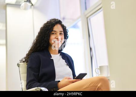 Young businesswoman having a break in the office while reading a text message Stock Photo
