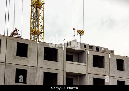 Construction site with the high crane building a grey block house in the city. Stock Photo
