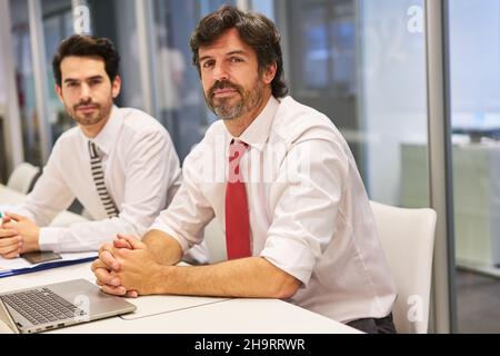 Two business people as self-confident consultants or lawyers in the office at the conference table Stock Photo