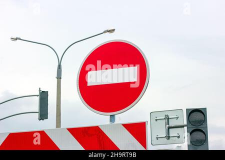 Red and white Do not enter and other signs on gray dull overcast sky background. Stock Photo