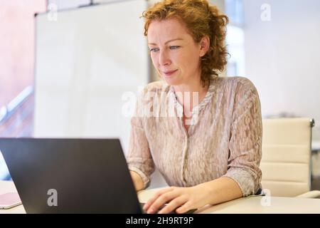 Business woman working on laptop computer online in office or as website developer Stock Photo