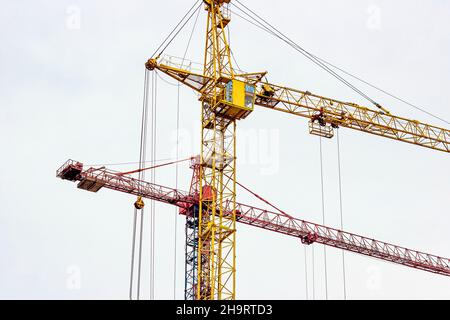 Two high cranes for house building at construction site on sky background. Stock Photo
