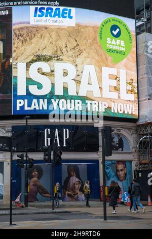 Pedestrians walk past an advertisement for Israeli tourism displayed on a large electric board in Piccadilly Circus, London. Stock Photo