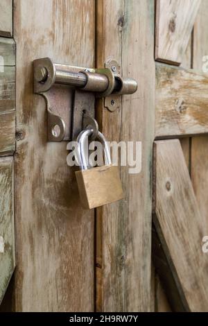 details of one closed padlock on the pin of a rustic wooden door, metal object texture, concept of locked entry and security