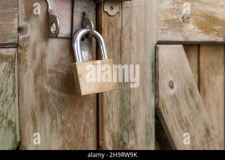 texture details of an old wooden door closed with one padlock, metal object texture, concept of locked entry and security as background Stock Photo
