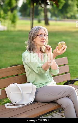 Woman looking in mirror sitting on bench Stock Photo