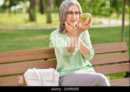 Elegant woman looking in mirror on bench Stock Photo