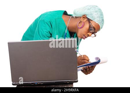 young female doctor taking notes on paper-press and working on laptop computer at the hospital. Stock Photo