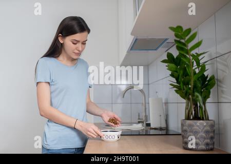 Serious dark-haired female holding pelleted feed in cupped hands Stock Photo