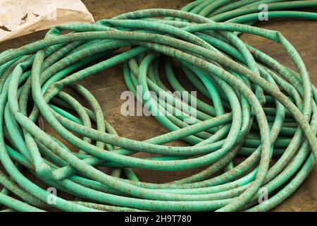 Coiled green rubber garden hoses with kinks. Stock Photo