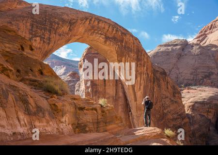 Glen Canyon National Recreation Area, Utah, USA. Photographer shooting backlit view of the huge sandstone arch of Rainbow Bridge National Monument. Stock Photo