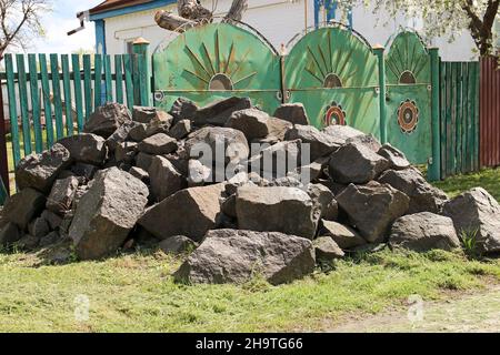 A pile of huge stones near the village house. Granite stones. Stock Photo