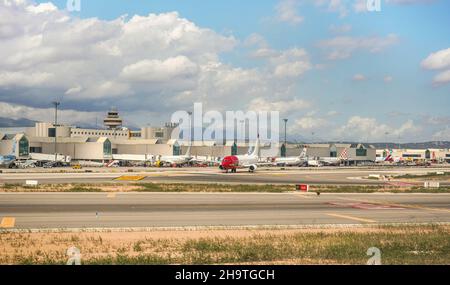 Palma, Spain - September 25, 2019: Various airlines aircrafts parked in front of airport building on sunny day, runway in foreground Stock Photo