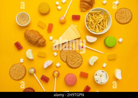 Variety of snacks and sweets on yellow background. Top view, flat lay. Sweet, dessert, diet concept. Stock Photo