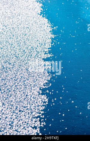 Surface of a frozen lake, half covered with snowflakes, half blue, vertical Stock Photo