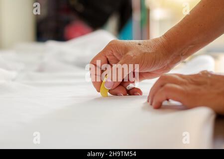 Female dressmaker's hands marking fabric for clothing design. Sewing work and clothing design. Stock Photo