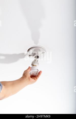 Mano replacing an energy saving light bulb in the ceiling of his room. Stock Photo